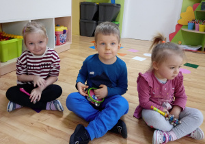 Dzieci siedzą trzymając instrumenty prekusyjne w dłoniach